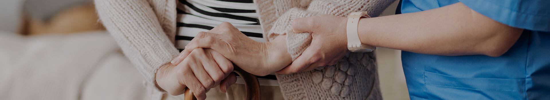 hands of nurse helping elderly person with a cane to stand or walk
