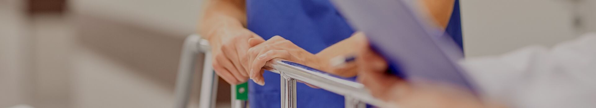 hands holding onto a gurney, clipboard in forefront